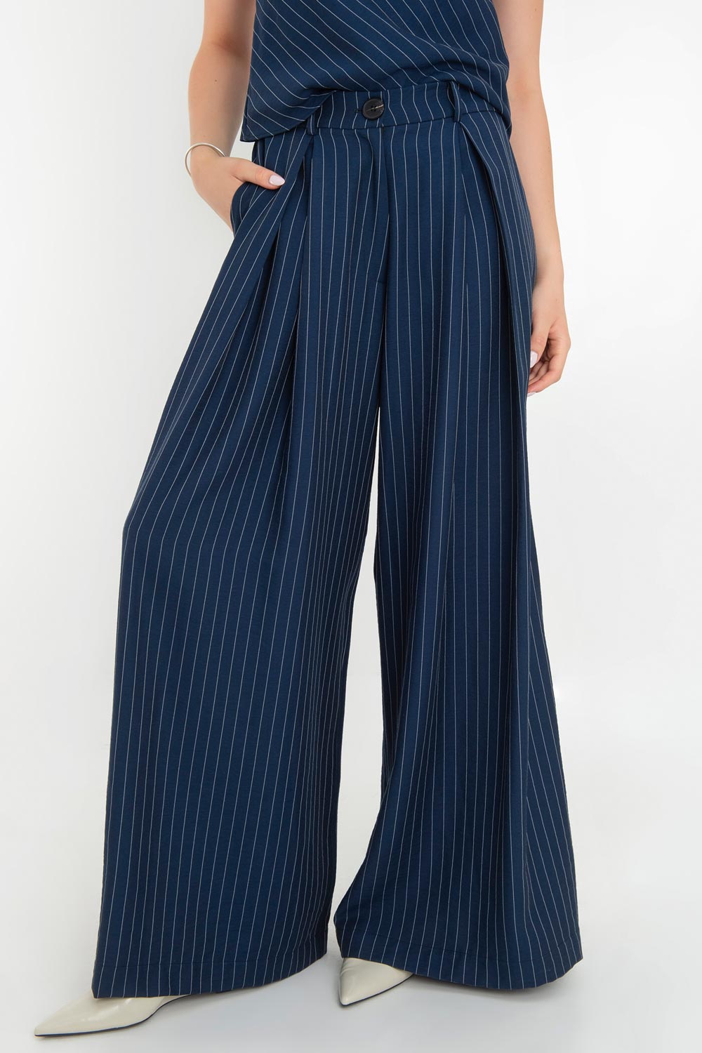 Pantalón de lino, estampado rayas, fit palazzo, cintura alta con pretina elástica posterior, trabillas, bolsillos delanteros y pinzas frontales. Cierre frontal con botón y cremallera oculta.