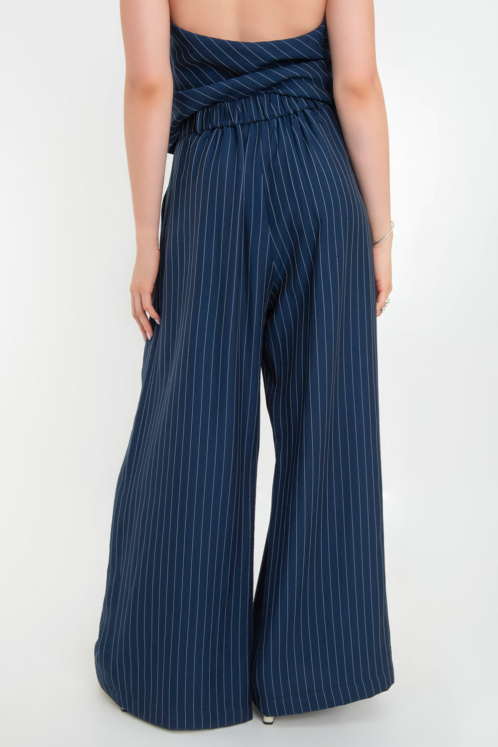 Pantalón de lino, estampado rayas, fit palazzo, cintura alta con pretina elástica posterior, trabillas, bolsillos delanteros y pinzas frontales. Cierre frontal con botón y cremallera oculta.