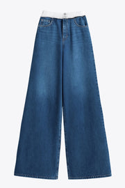 Pantalón wide leg de denim, cintura alta con pretina elástica en constraste, bolsillos delanteros y posteriores de parche. Cierre frontal con botones y cremallera oculta.
