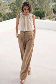 Pantalón de fit wide leg, cintura alta con pretina, trabillas y doble lazo amarrable, pinzas frontales y bolsillos delanteros. Cierre frontal con broche y cremallera ocultos.