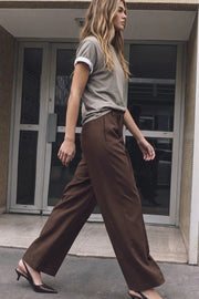 Pantalón de fit wide leg, cintura alta con pretina, trabillas y doble lazo amarrable, pinzas frontales y bolsillos delanteros. Cierre frontal con broche y cremallera ocultos.