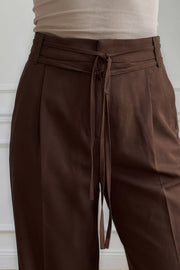 Pantalón de fit wide leg, cintura alta con pretina, trabillas y doble lazo amarrable, pinzas frontales y bolsillos delanteros. Cierre frontal con broche y cremallera ocultos.