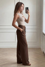 Pantalón de fit wide leg, cintura alta con pretina, trabillas y doble lazo amarrable, pinzas frontales y bolsillos delanteros. Cierre frontal con broche y cremallera ocultos.