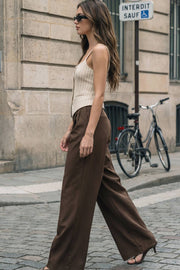 Pantalón de fit wide leg, cintura alta, pretina con detalle v posterior y trabillas, pinzas frontales, bolsillos delanteros y vivos decorativos posteriores. Cierre frontal con botón en contraste y cremallera ocultas.