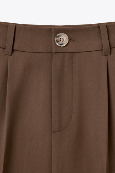 Pantalón de fit wide leg, cintura alta, pretina con detalle v posterior y trabillas, pinzas frontales, bolsillos delanteros y vivos decorativos posteriores. Cierre frontal con botón en contraste y cremallera ocultas.