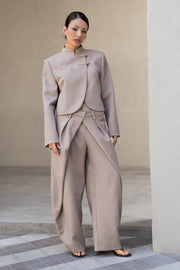 Pantalón fit barrel de cintura media, cruce doble decorativo con pretina y trabillas, pinzas frontales y vivos decorativos posteriores. Cierre frontal con broche y cremallera ocultos.