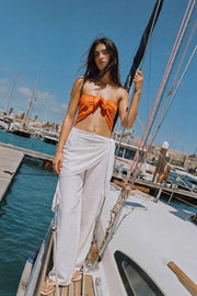 Pantalón fluido de fit palazzo, cintura media con pretina elástica, plisados en costado y detalle de pareo decorativo con nudo lateral.