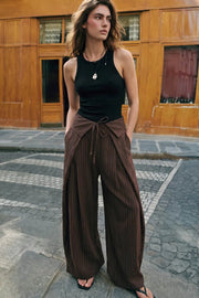 Pantalón de estampado rayas, fit palazzo, cintura alta, pretina con solapa y lazo amarrable frontal, pinzas frontales con detalles decorativos y bolsillos delanteros. Cierre frontal con botón y cremallera oculta.