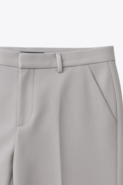 Pantalón de fit recto, cintura alta con pretina y trabillas, bolsillos delanteros y posteriores decorativos con cartera, raya frontal, cierre con broche y cremallera ocultos.