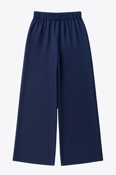 Pantalón fluido de fit wide leg, cintura alta con pretina elástica posterior, trabillas, pinzas frontales y bolsillos delanteros.