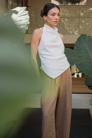 Pantalón fluido de fit recto, con pinzas frontales, cintura alta con pretina elástica posterior, bolsillos delanteros, cierre frontal con botón y cremallera oculta.