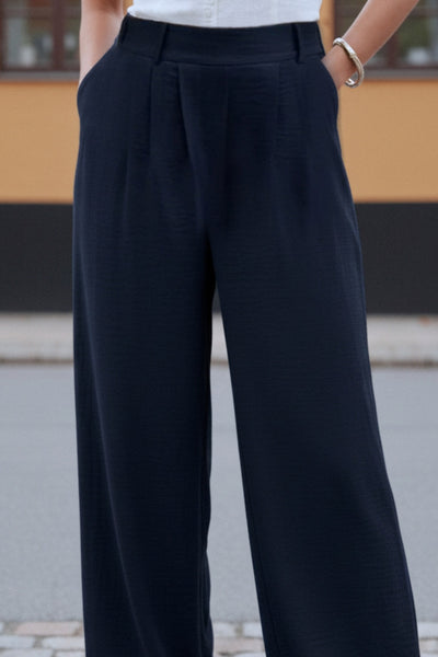 Pantalón fluido de fit wide leg, pinzas frontales, bolsillos delanteros y cintura alta con pretina elástica posterior.