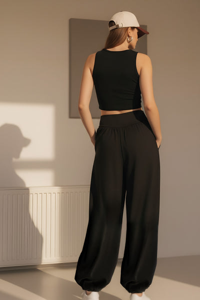 Pantalón de fit harem, cintura alta, peto con corte v frontal y plisado decorativos, rib elástico en bajo y cierre lateral con cremallera oculta.