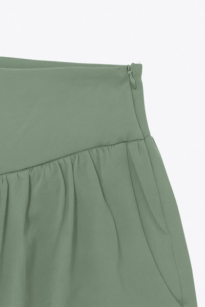 Pantalón de fit harem, cintura alta, peto con corte v frontal y plisado decorativos, rib elástico en bajo y cierre lateral con cremallera oculta.