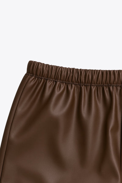 Pantalón de efecto piel, fit recto, bolsillos delanteros, cintura alta con pretina elástica y jareta frontal ajustable. Detalle de costuras posteriores decorativas.