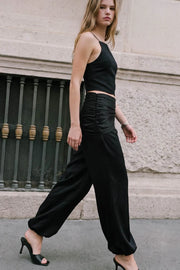 Pantalón satinado de fit balloon, cintura media elástica, bolsillos delanteros, detalle de pareo decorativo con plisados y nudo lateral.