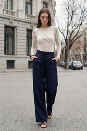 Pantalón de fit wide leg, cintura alta con pretina, trabillas y doble lazo amarrable, pinzas frontales y bolsillos delanteros. Cierre frontal con broche y cremallera ocultos.