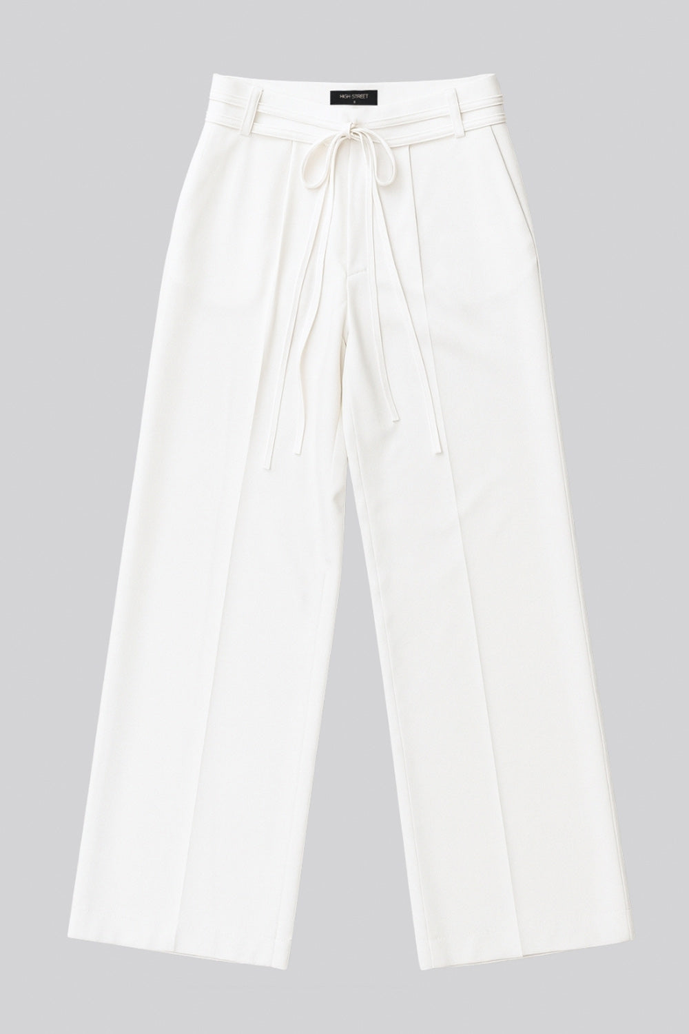 Pantalón de fit wide leg, cintura alta con pretina, trabillas y doble lazo amarrable, pinzas frontales y bolsillos delanteros. Cierre frontal con broche y cremallera ocultos.