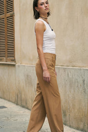 Pantalón de fit recto, cintura media con pretina ancha y trabillas, bolsillos delanteros y vivos decorativos posteriores. Cierre frontal con botones y cremallera oculta.