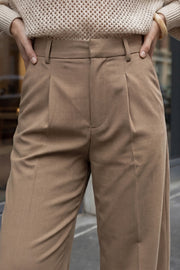 Pantalón de fit recto, pinzas frontales, cintura alta con pretina y trabillas, bolsillos delanteros, cierre frontal con broche y cremallera ocultos.