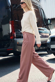 Pantalón de fit wide leg, cintura alta con pretina elástica posterior y trabillas, doble pinza frontal, bolsillos delanteros y detalle de raya frontal. Cierre frontal con broche y cremallera ocultos.