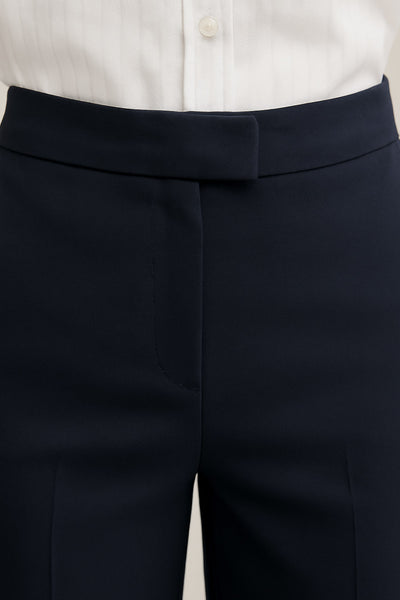 Pantalón ajustado de fit flare, cintura media con pretina, bolsillos delanteros y vivos decorativos posteriores. Cierre frontal con broche y cremallera ocultos.