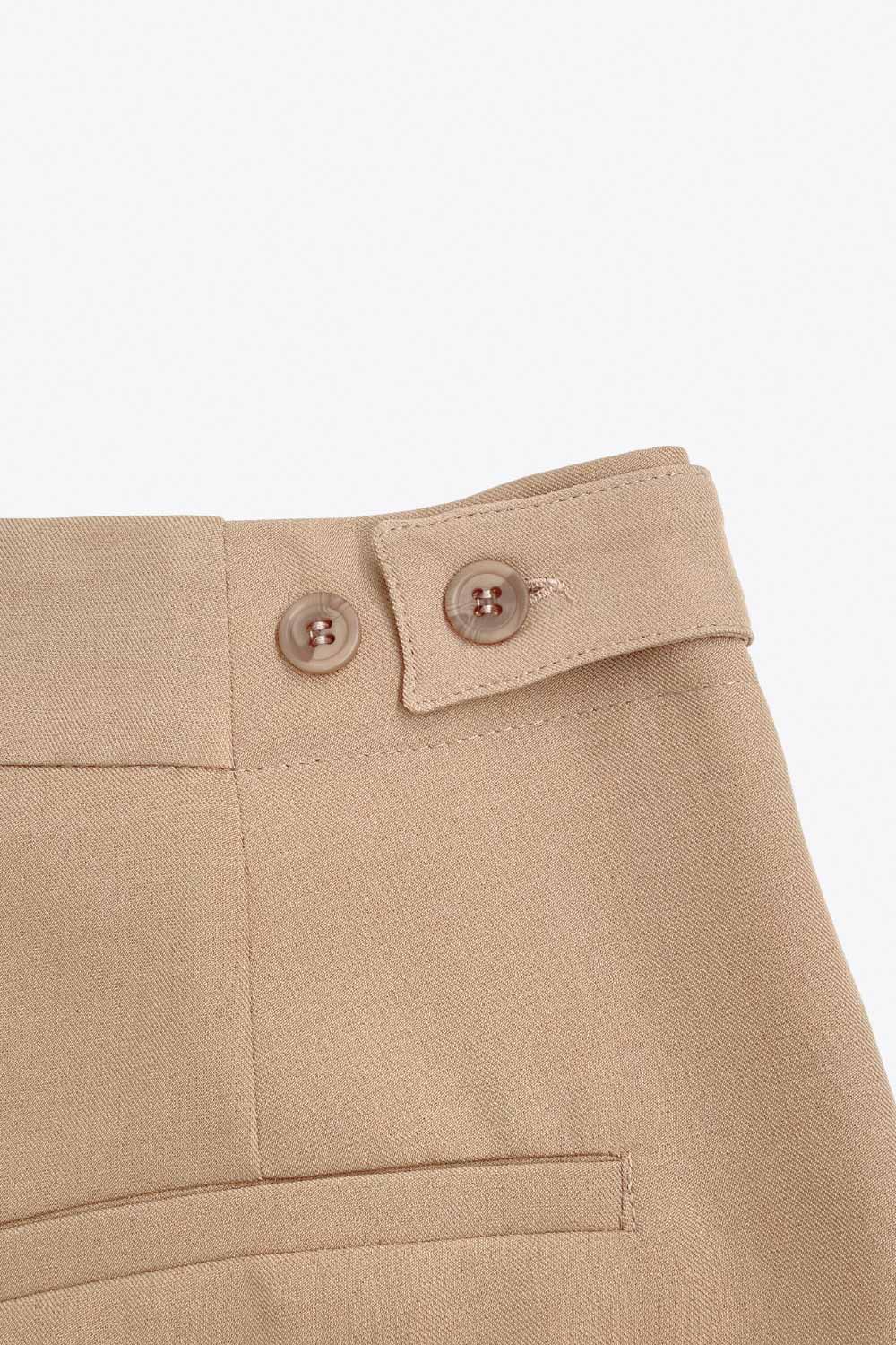 Pantalón de fit wide leg, cintura media con pretina, trabillas ajustables laterales, pinzas frontales, bolsillos delanteros y vivos decorativos posteriores. Cierre frontal con broche y cremallera ocultos.