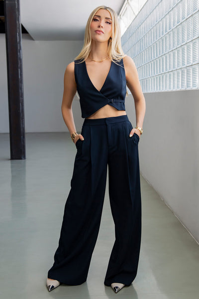 Pantalón de fit wide leg, cintura alta con pretina, pinzas frontales, bolsillos delanteros y vivos decorativos posteriores. Cierre frontal con broche y cremallera ocultos. Detalle v en pretina posterior.