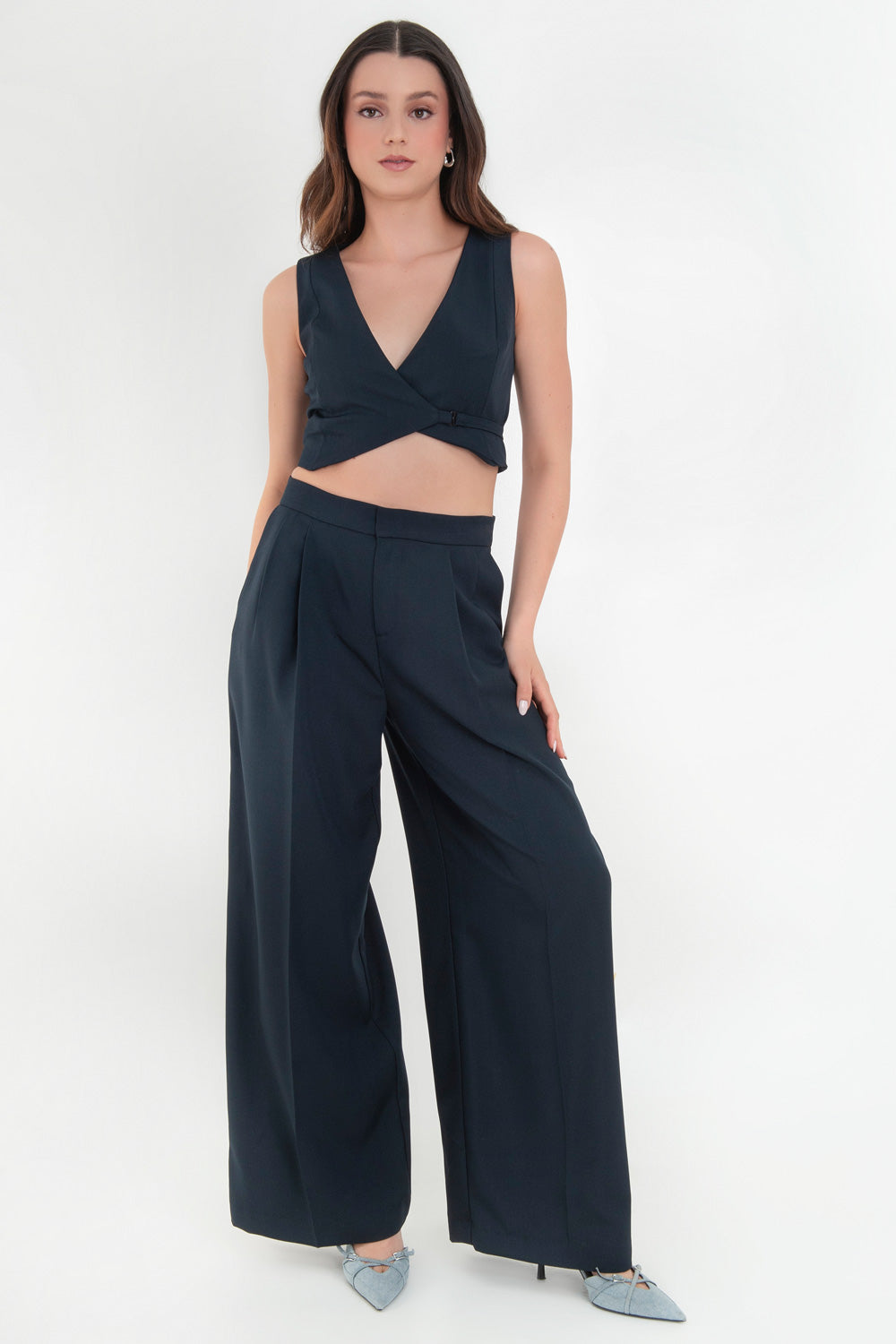 Pantalón de fit wide leg, cintura alta con pretina, pinzas frontales, bolsillos delanteros y vivos decorativos posteriores. Cierre frontal con broche y cremallera ocultos. Detalle v en pretina posterior.