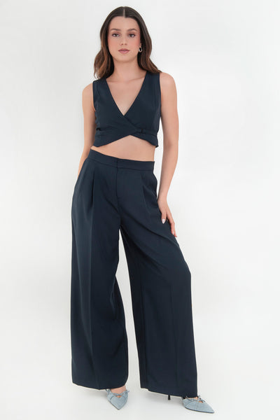 Pantalón de fit wide leg, cintura alta con pretina, pinzas frontales, bolsillos delanteros y vivos decorativos posteriores. Cierre frontal con broche y cremallera ocultos. Detalle v en pretina posterior.