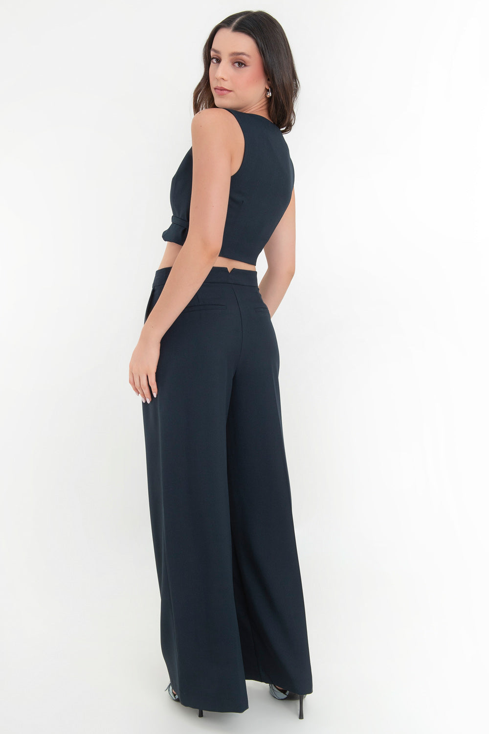 Pantalón de fit wide leg, cintura alta con pretina, pinzas frontales, bolsillos delanteros y vivos decorativos posteriores. Cierre frontal con broche y cremallera ocultos. Detalle v en pretina posterior.