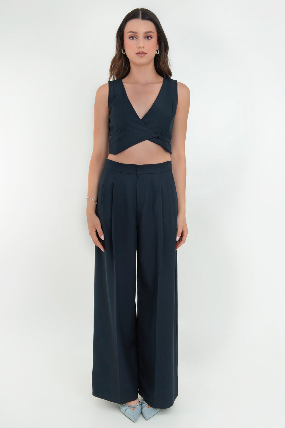 Pantalón de fit wide leg, cintura alta con pretina, pinzas frontales, bolsillos delanteros y vivos decorativos posteriores. Cierre frontal con broche y cremallera ocultos. Detalle v en pretina posterior.