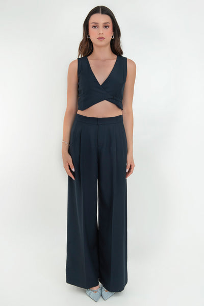 Pantalón de fit wide leg, cintura alta con pretina, pinzas frontales, bolsillos delanteros y vivos decorativos posteriores. Cierre frontal con broche y cremallera ocultos. Detalle v en pretina posterior.