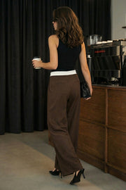 Pantalón de fit wide leg, pinzas frontales, cintura media, pretina con detalle de tailoring en contraste, bolsillos delanteros y vivos decorativos posteriores. Cierre frontal con broche y cremallera ocultos.