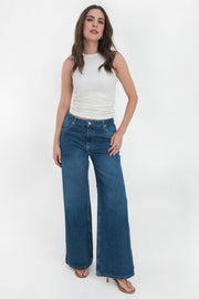 Pantalón wide leg de denim, cintura alta con pretina y trabillas, bolsillos delanteros y posteriores de parche. Cierre frontal con botón y cremallera oculta.