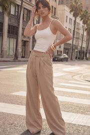 Pantalón de fit wide leg, cintura alta con pretina elástica posterior, trabillas, pinzas frontales y bolsillos delanteros.