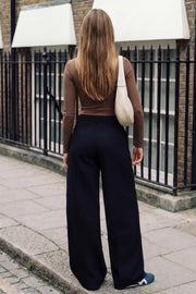 Pantalón de fit wide leg, pinzas frontales, cintura alta con pretina y trabillas, bolsillos delanteros, cierre frontal con broche y cremallera ocultos.