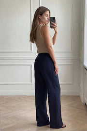 Pantalón de fit recto, pinzas frontales, cintura alta con pretina elástica posterior y trabillas, bolsillos delanteros, vivo decorativo posterior, cierre frontal con broche y cremallera ocultos.