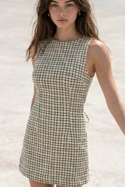 Playsuit de estampado cuadros, fit ajustado, cuello barco, sin mangas, pinzas frontales, lazo amarrable posterior y cierre con cremallera oculta.