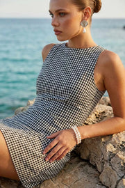 Playsuit de estampado cuadros, fit ajustado, cuello barco, sin mangas, pinzas frontales, lazo amarrable posterior y cierre con cremallera oculta.