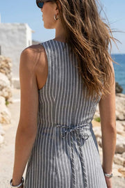 Playsuit de estampado rayas, fit ajustado, cuello barco, sin mangas, pinzas frontales, lazo amarrable posterior y cierre con cremallera oculta.