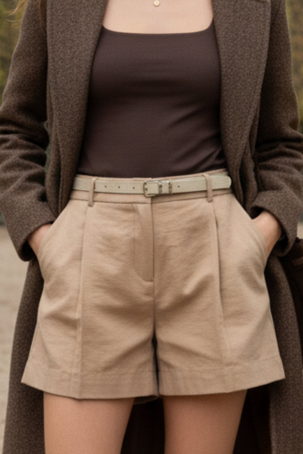 Short corto de fit recto, pinzas frontales, cintura alta con pretina y trabillas, bolsillos delanteros y vivos decorativos posteriores. Cierre frontal con broche y cremallera ocultos. Detalle de cinturón con hebilla en contraste.