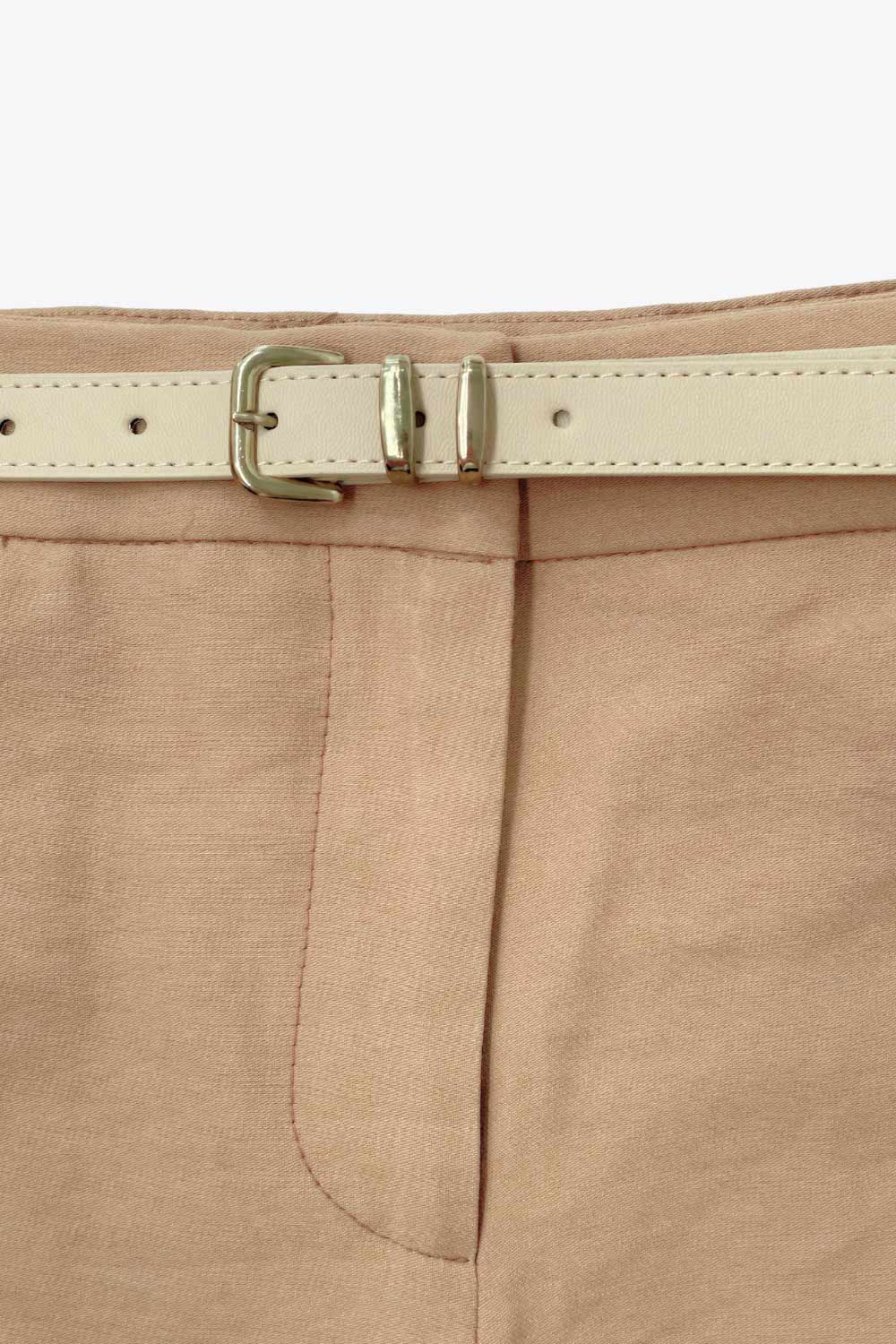 Short corto de fit recto, pinzas frontales, cintura alta con pretina y trabillas, bolsillos delanteros y vivos decorativos posteriores. Cierre frontal con broche y cremallera ocultos. Detalle de cinturón con hebilla en contraste.