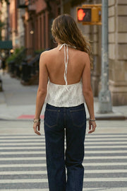 Top corto de escote v con lazo amarrable frontal, rib elástico en espalda, tirantes halter con lazo amarrable posterior y abertura frontal en bajo. Detalle de peplum olanes en bajo y textura en tejido.