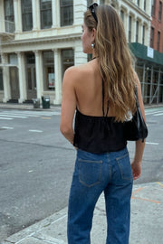 Top corto de escote v con lazo amarrable frontal, rib elástico en espalda, tirantes halter con lazo amarrable posterior y abertura frontal en bajo. Detalle de peplum olanes en bajo y textura en tejido.