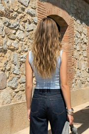 Top de fit ajustado, sin mangas, cuello fluido y plisados decorativos en hombros.