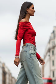 Top de fit ajustado, hombros descubiertos, escote recto y manga larga seguida con plisados laterales. Detalle de plisados en costados.