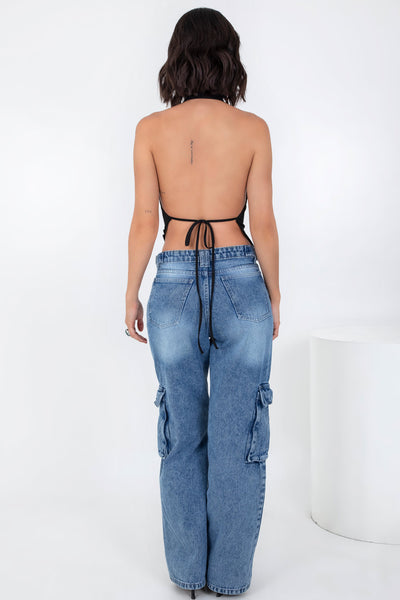 Top asimétrico de fit ajustado, cuello halter con escote fluido, sin mangas, bajo asimétrico frontal, escote en espalda y cierre posterior con lazo amarrable.