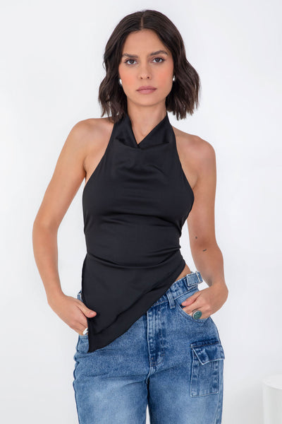 Top asimétrico de fit ajustado, cuello halter con escote fluido, sin mangas, bajo asimétrico frontal, escote en espalda y cierre posterior con lazo amarrable.