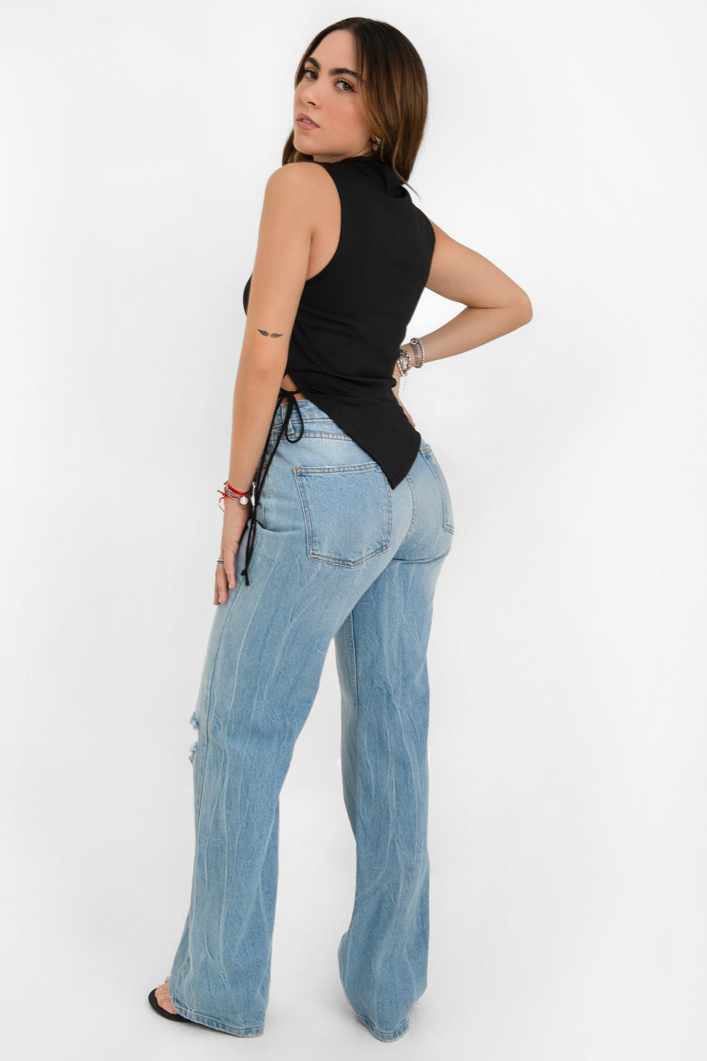 Top asimétrico de fit recto, cuello barco, sin mangas, bajo asimétrico diagonal con abertura lateral y lazo amarrable decorativo.